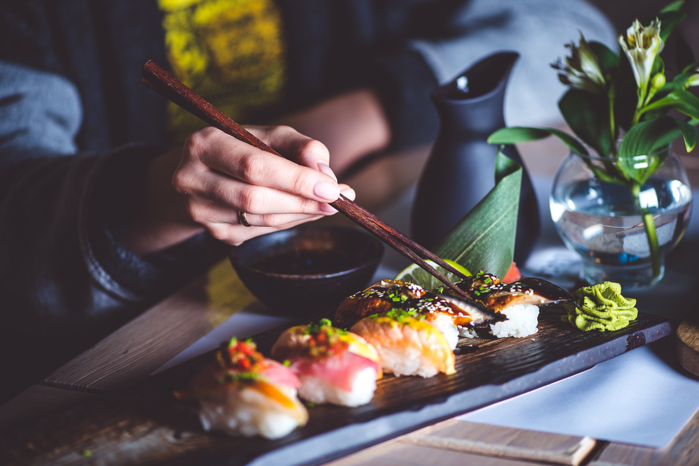 Man,Eating,Sushi,Set,With,Chopsticks,On,Restaurant